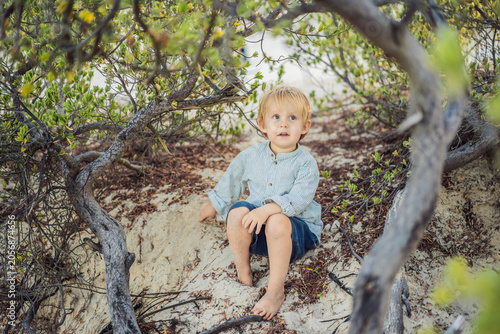 Cute three year old toddler playing on tropical beach during summer vacation. Happy childhood, family travel and carefree lifestyle concept by the ocean