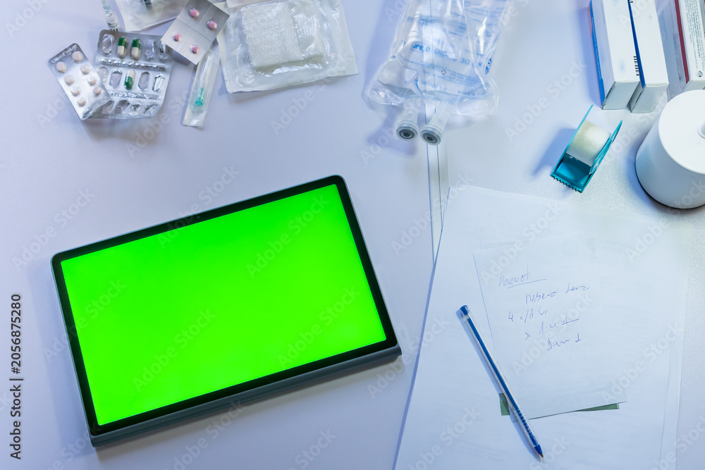 Fototapeta premium Medical supplies and digital tablet with green screen on a doctor's desk