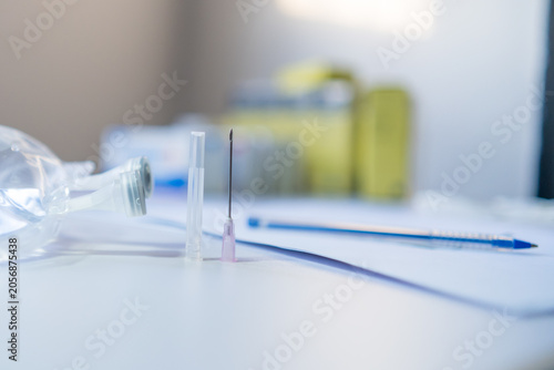 Medical supplies including IV bag, syringe needle, and pen on a white surface