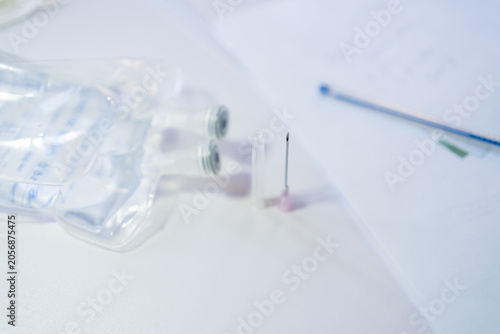 Photos Medical intravenous fluid bags and a sharp needle with protective cap on a clean