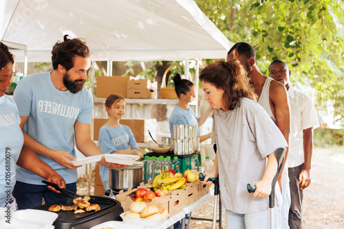 Fotografija Multiethnic group of volunteers providing humanitarian aid to disadvantaged individuals, with caring charity workers distribute free food and donations, helping the homeless, sick, and needy people
