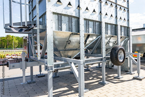 Obraz na plátně Large stainless steel industrial hopper mounted on a sturdy metal support frame standing on a concrete pad outdoors