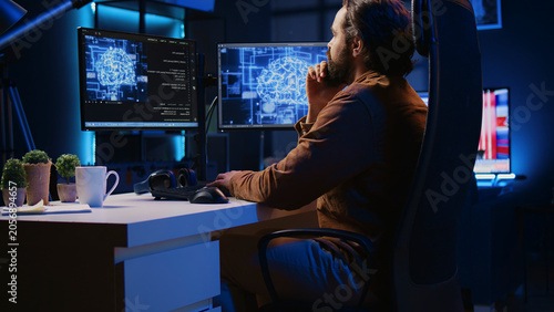 Bilde på lerret Freelancing programmer writes code on desktop PC to visualize artificial intelligence neural networks, self employed man runs AI script on computer from apartment office, jib down shot