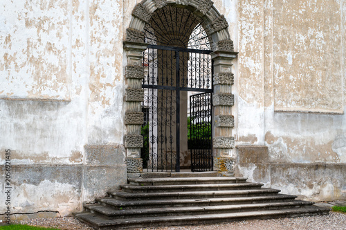 Ornate Iron Gate in Weathered Stone Archway With Steps at Historic Building Entrance
