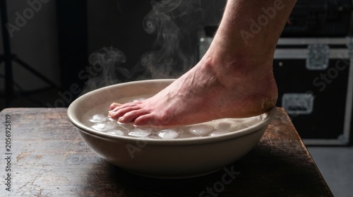 Man soaking injured foot in ice water bath for ankle sprain relief