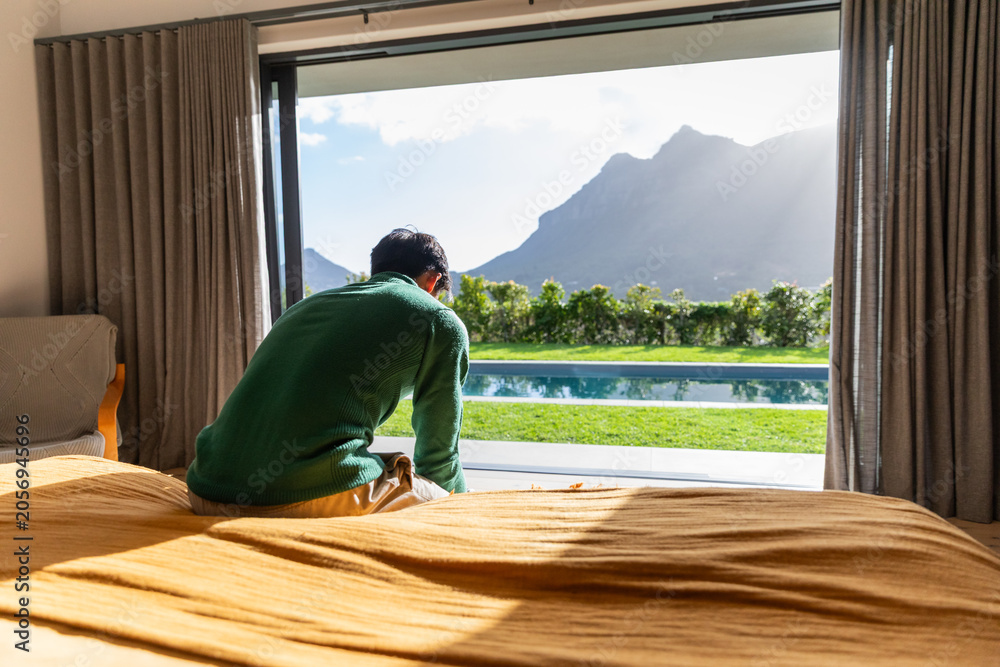 Obraz premium Mustard duvet is covering bed in bedroom while sliding glass door is revealing pool and mountains