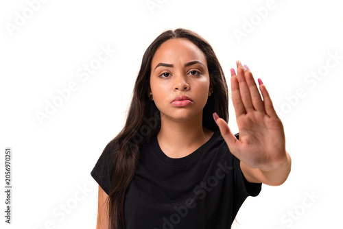 Serious young latina woman showing stop gesture isolated on white background.