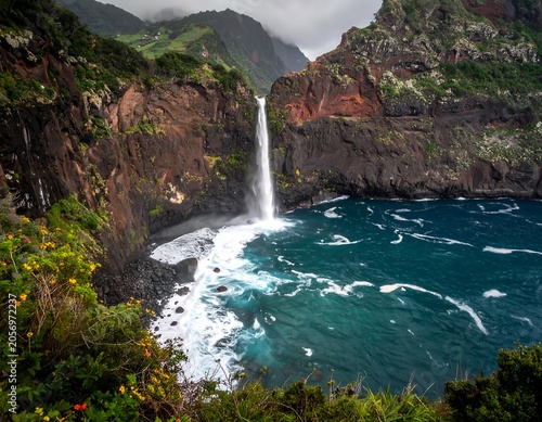 A breathtaking waterfall cascades into the ocean, surrounded by rugged cliffs and lush greenery