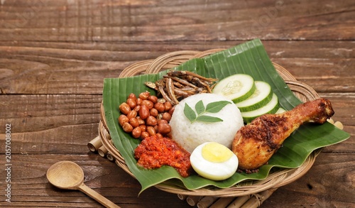 nasi lemak served on a plate with fragrant coconut rice, spicy sambal, fried anchovies, roasted peanuts, boiled egg, and fresh cucumber slices