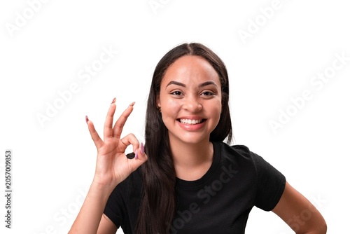 Happy young latina woman smiling and showing ok hand gesture isolated on white background.