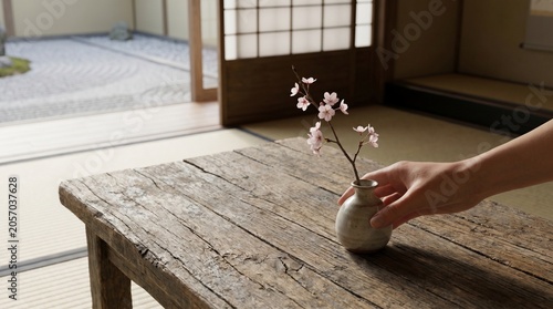 Hand holding cherry blossom vase on wooden table in Japanese room