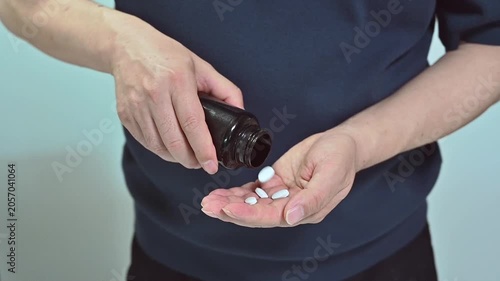 검은 병에서 손바닥으로 흰색 알약을 쏟아붓는 남성의 클로즈업, 헬스케어 및 일상적인 약물 복용 개념