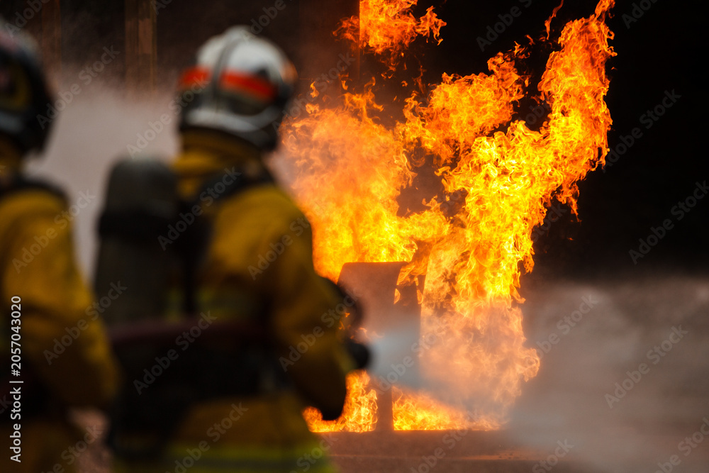 Fototapeta premium Firefighters tackling a large intense blazing fire outdoors
