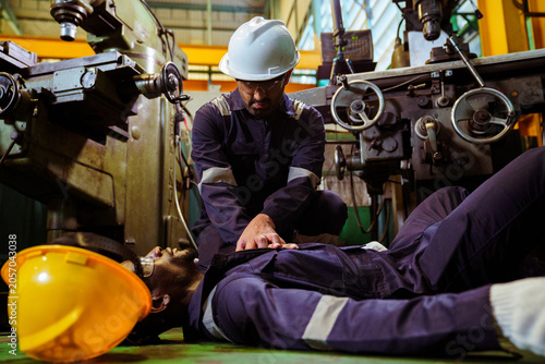 Factory worker performing cpr on unconscious colleague