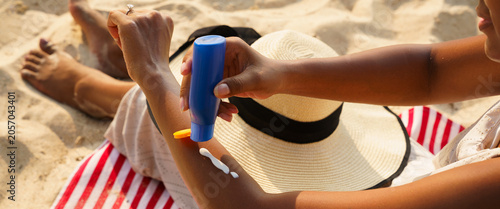 Black woman applying sunscreen or sunblock lotion on the beach