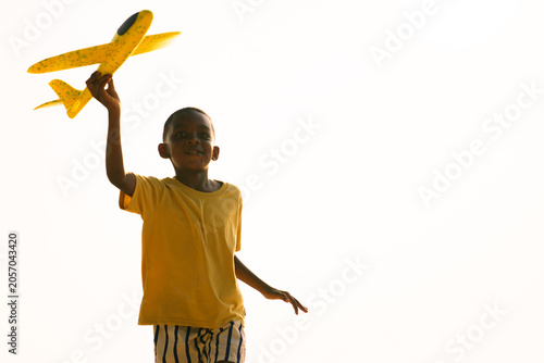 Happy boy running with toy air plane on summer beach