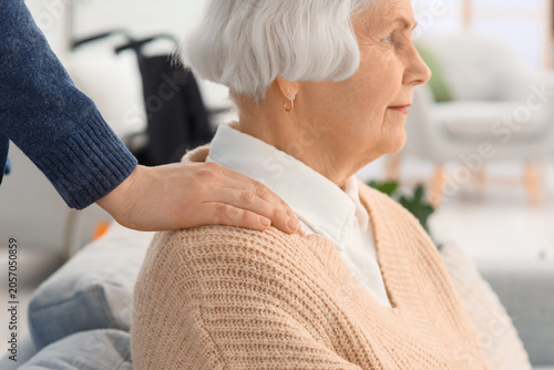 Caregiver hugging senior woman with dementia at home, closeup
