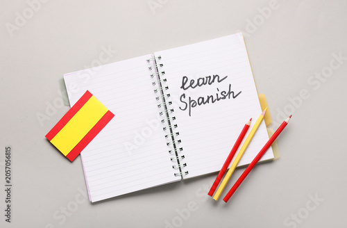 Fotografie Learn spanish language education with notebook, pencils, and flag on gray backgr
