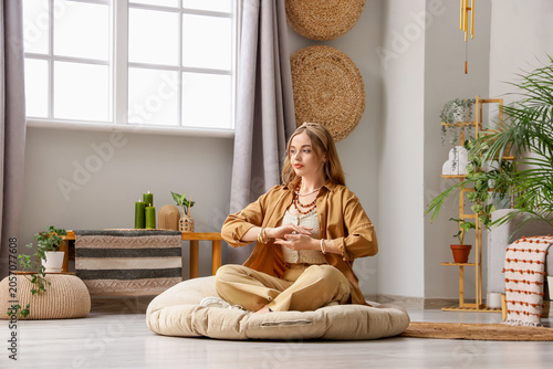 Fotografía Beautiful young woman meditating on pouf at home. Zen concept