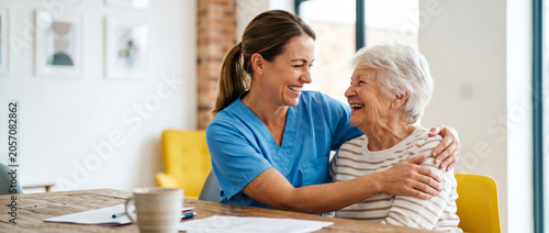 Smiling female nurse affectionately embracing a happy senior woman at a care home