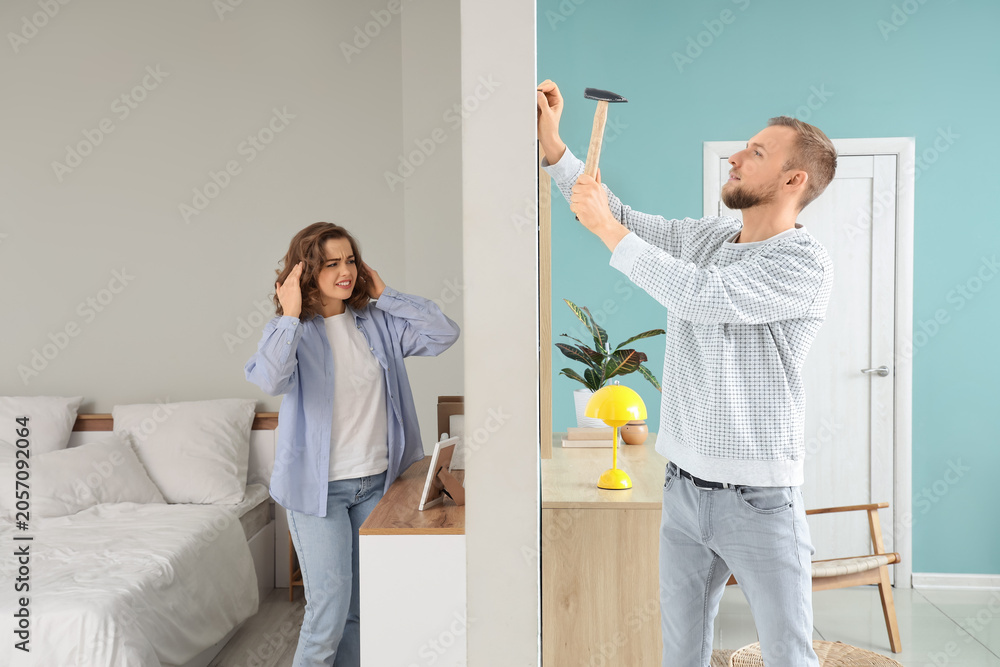 Ταπετσαρία Young woman suffering from noisy neighbour hammering nail at home