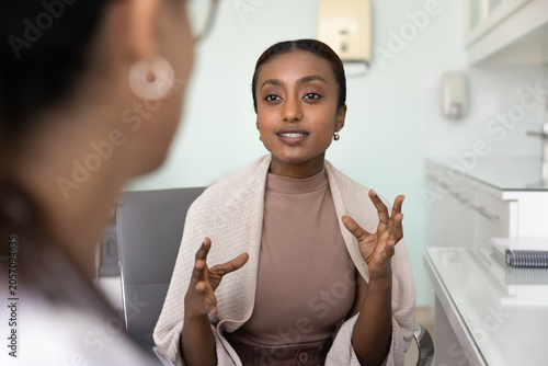 Fotografie Happy young African American patient woman talking to female doctor, visiting ge