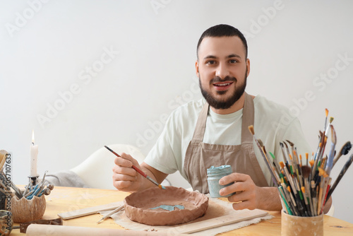 Smiling male potter paintin...