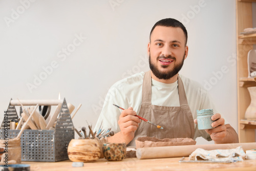 Smiling male potter paintin...