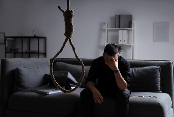Hanging rope with loop against businessman in dark office. International Stress Awareness Week