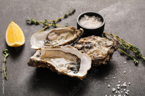 Obraz na plátně Fresh raw oysters with lemon wedge, sea salt, and thyme sprigs on dark stone bac