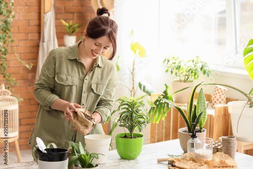 Young woman pouring soil in...