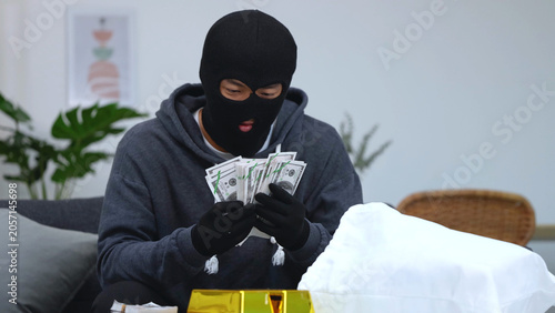 Tableau sur toile Masked Criminal in Balaclava Counting Stolen Cash Indoors Near Gold Bars