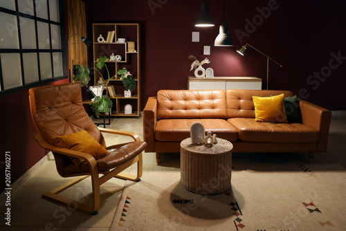 Cozy living room interior with brown leather sofa, armchair, and modern decor elements