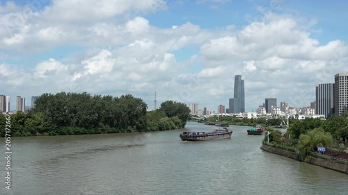 Urban River Scene with Cargo Boats and Modern City Skyline