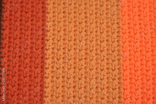 A close up of a striped orange and brown sweater. The sweater is knitted and has a striped pattern