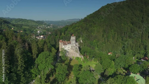 Stunning high altitude reverse panoramic orbit over magnificent Bran Castle and surrounding Transylvanian countryside in early summer, cinematic drone reveal