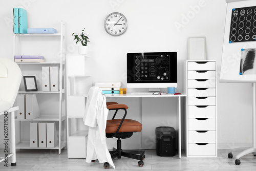Modern medical office interior with computer displaying patient card and doct...