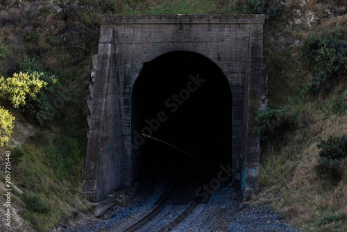 Photography Railroad tracks disappearing into a dark concrete tunnel