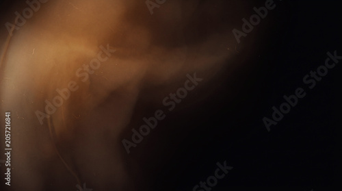 A subtle abstract composition featuring a gentle warm brown light leak blooming softly from the upper corner against a pure solid black background