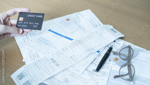 Credit card on financial documents with receipts, pen and glasses, showing monthly bills, household expenses and credit card spending.