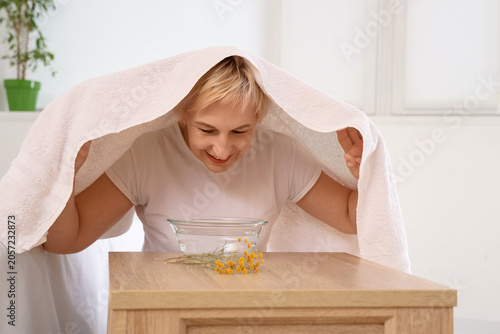 Foto Mature woman doing steam inhalation at table in bedroom