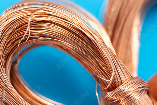 High quality close up of bright copper wire on a blue background. Perfect for industrial, electrical, and recycling concepts. Shiny metallic texture for engineering and technology.