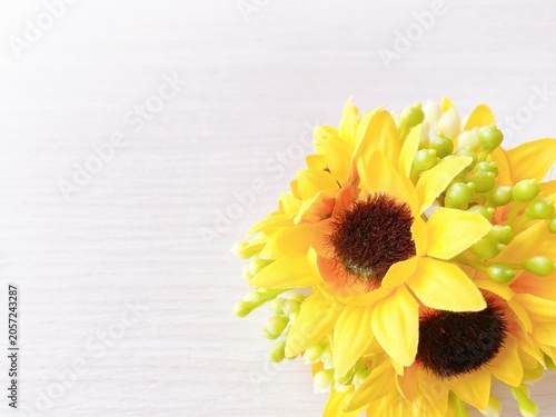 Artificial yellow sunflower bouquet on a light wooden background with copy space