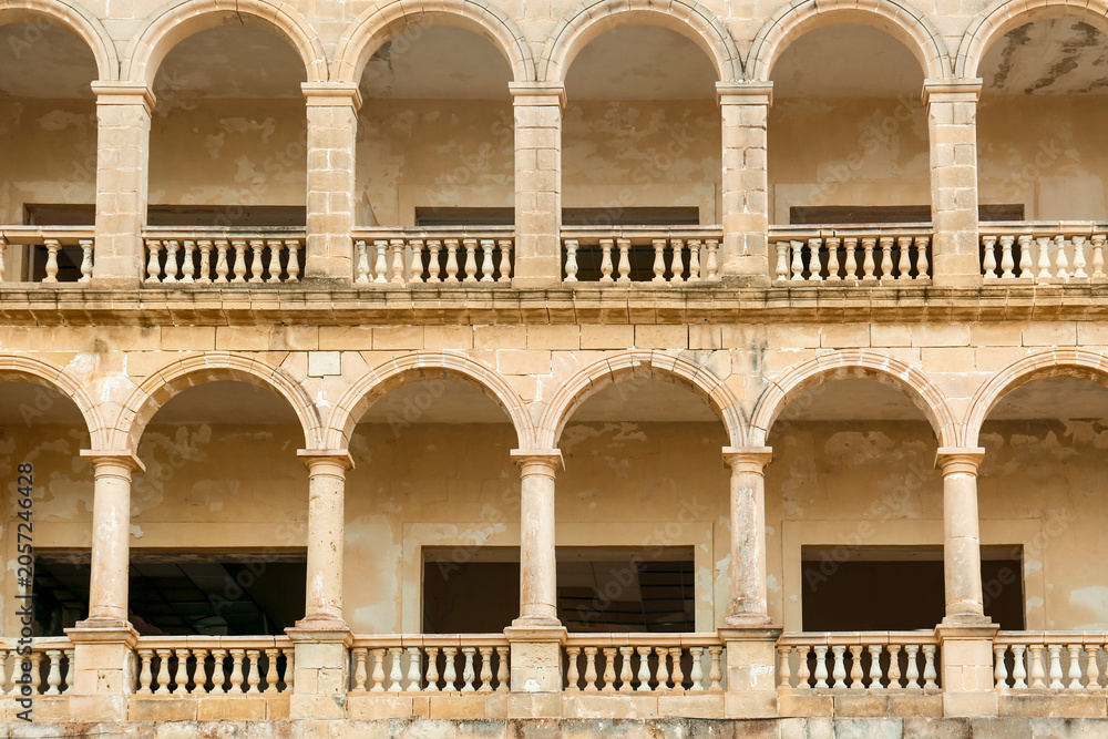 Naklejka premium Historic stone archways and balustrades of an abandoned building facade, architectural detail and decay, the weathered stone columns and arches show signs of decay and neglect