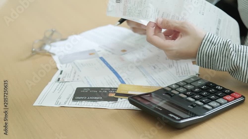 Hands checking long receipts with a calculator, credit card and financial documents for household expense tracking and monthly debt planning.