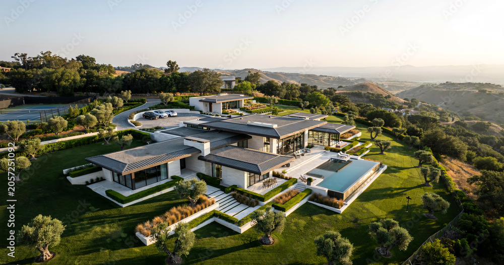 Obraz premium Modern Luxury Villa with Swimming Pool on a Green Hillside at Sunset