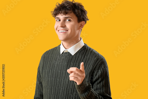 Portrait of handsome young man pointing at camera on orange background