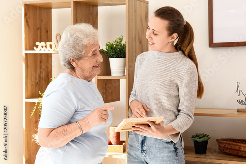 Senior woman with her granddaughter and photo frame at home