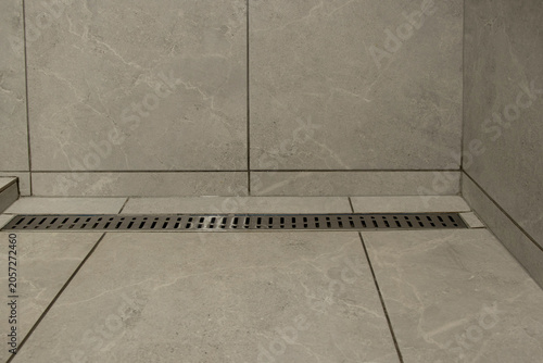 Linear drain in a shower area with gray tiles, a solution for water drainage