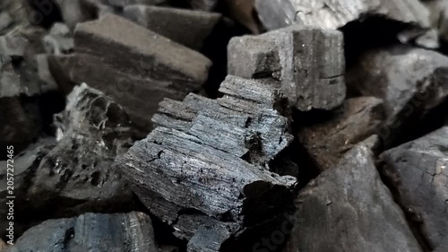 A collection of charcoal. Charcoal is a black, carbonaceous residue produced by burning wood without oxygen (pyrolysis). This material is widely used as a cooking fuel